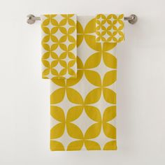 two yellow and white towels hanging on a towel rack in front of a white wall