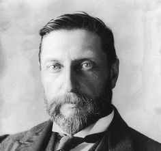 an old black and white photo of a man with a beard wearing a suit jacket