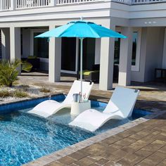 two lawn chairs and an umbrella sitting in the middle of a swimming pool next to a house