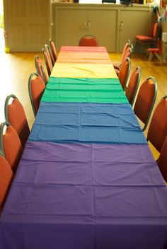 there is a long table with many chairs around it and the colors are multicolored