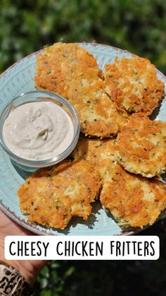 chicken fritters on a plate with ranch dip in the middle and text overlay that reads cheesy chicken fritters