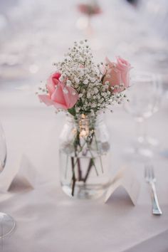 a vase filled with pink roses and baby's breath sitting on top of a table