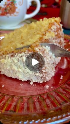 a piece of cake on a glass plate with a fork and cup in the background