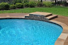 an empty swimming pool with steps leading up to the edge and grass in the background