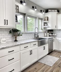 a clean kitchen with white cabinets and wood flooring is seen in this image from the front view