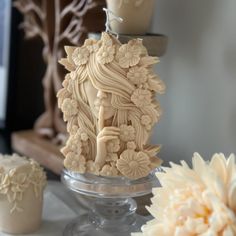 an intricately carved ivory figurine sits on a table next to flowers and candles