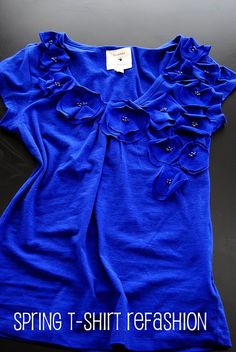 a blue t - shirt with ruffles on the front and bottom, sitting on a black surface