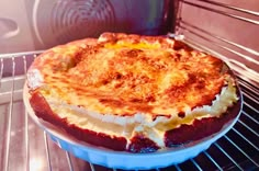 a baked dish sitting in an oven on top of a plate with cheese and sauce