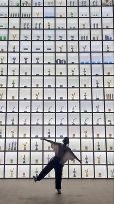 a person standing in front of a wall with many awards on it