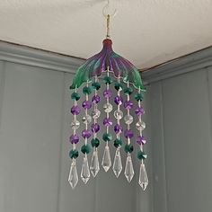 a chandelier hanging from the ceiling with purple and green beaded glass beads