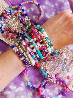 a close up of a person's arm with bracelets and beads on it