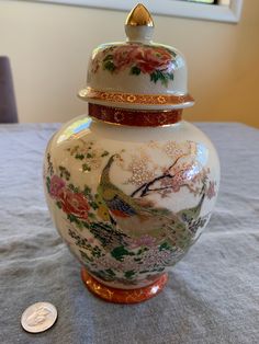 a white vase sitting on top of a table next to a coin