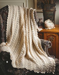 an old fashioned crocheted blanket sitting on top of a wooden table next to a chair