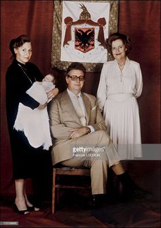 an old photo of two women and a man with a baby in front of a flag