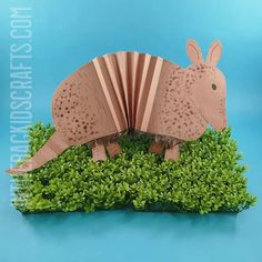 an origami rhinoceros is sitting on top of some green plants and grass