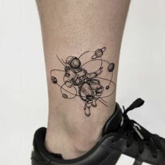 a small tattoo on the leg of a person with an astronaut and planets design on it