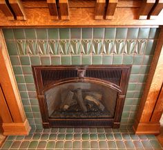 a fireplace with green tiles and wood trim