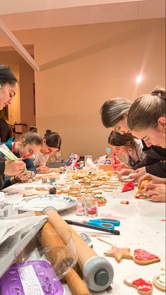 a group of people sitting at a table making cookies