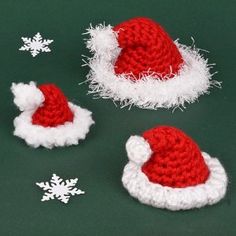 three crocheted santa hats sitting on top of a green surface