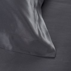 close up view of an unmade bed with grey sheets and pillow cases on it