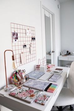 a white desk topped with lots of different types of papers and pens on top of it