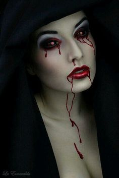 a woman with blood on her face and black hood over her head is staring at the camera