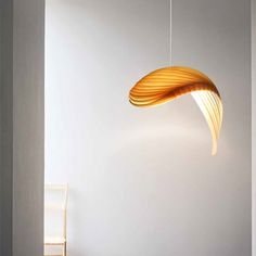 a lamp hanging from the ceiling in a room with white walls and wooden flooring