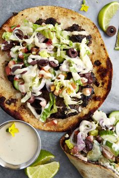 two pita breads filled with salad and dressing next to a small bowl of ranch dressing