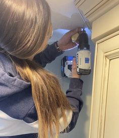 a woman using a power drill to fix a cabinet door