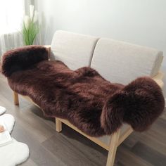 a brown and white couch sitting on top of a wooden floor next to a window