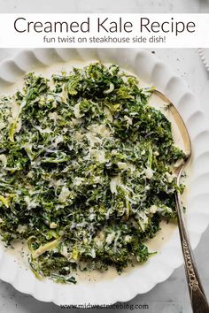 a white plate topped with spinach and cheese next to a silver spoon on top of a table