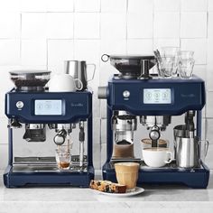 two espresso machines sitting next to each other on top of a white counter