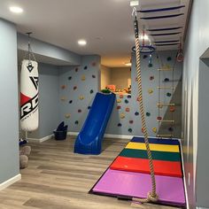 a child's play room with climbing wall, slide and gym equipment in it