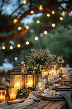 an outdoor dinner table with candles and plates