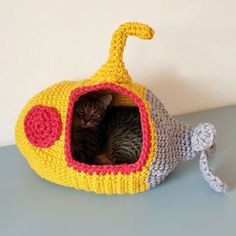 a cat is sitting in a crocheted toy submarine