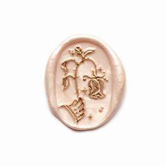 a pink wax stamp with an image of a woman's face and hands on it