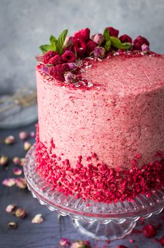 a cake with pink frosting and red sprinkles on the top is sitting on a glass plate