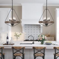 a kitchen island with four chairs and a bowl of flowers on the counter next to it