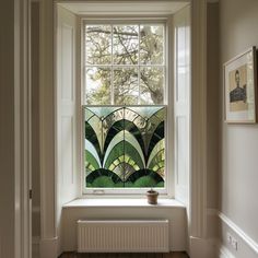 a window in a white room with green art deco tiles on the windowsill and wood flooring