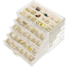 three clear drawers filled with jewelry on top of each other in front of a white background