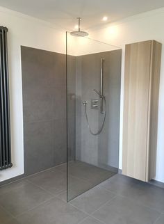 a bathroom with a glass shower door next to a radiator on the wall