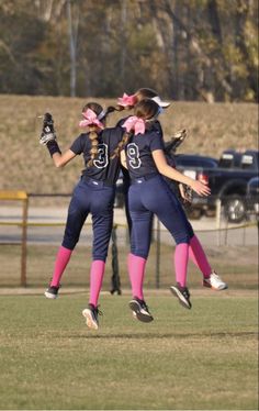 two girls are jumping in the air to catch a frisbee while playing softball