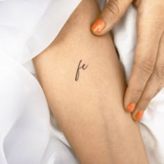 a woman's leg with the word fe tattooed on it in cursive font