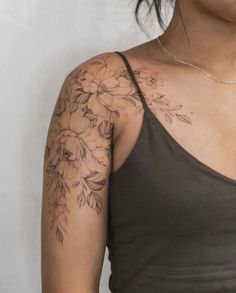 a woman wearing a tank top with flowers on her arm and chest tattooing it's upper half