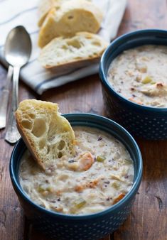 two blue bowls filled with soup on top of a wooden table next to a spoon