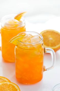 two mason jars filled with orange juice and garnished with an orange slice on the rim