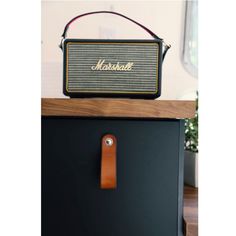 an old marshall amp sitting on top of a black cabinet next to a brown leather keychain