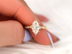 a woman's hand holding an engagement ring with a star shaped diamond on it