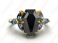 a black diamond and blue topazte ring with yellow gold accents on the sides