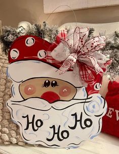 a santa clause sign sitting on top of a shelf next to some christmas decorations and pillows